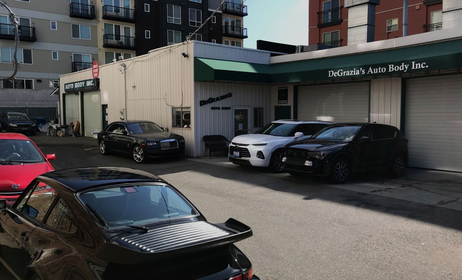 A lot of cars are parked in front of Degrazia 's Auto Body Inc