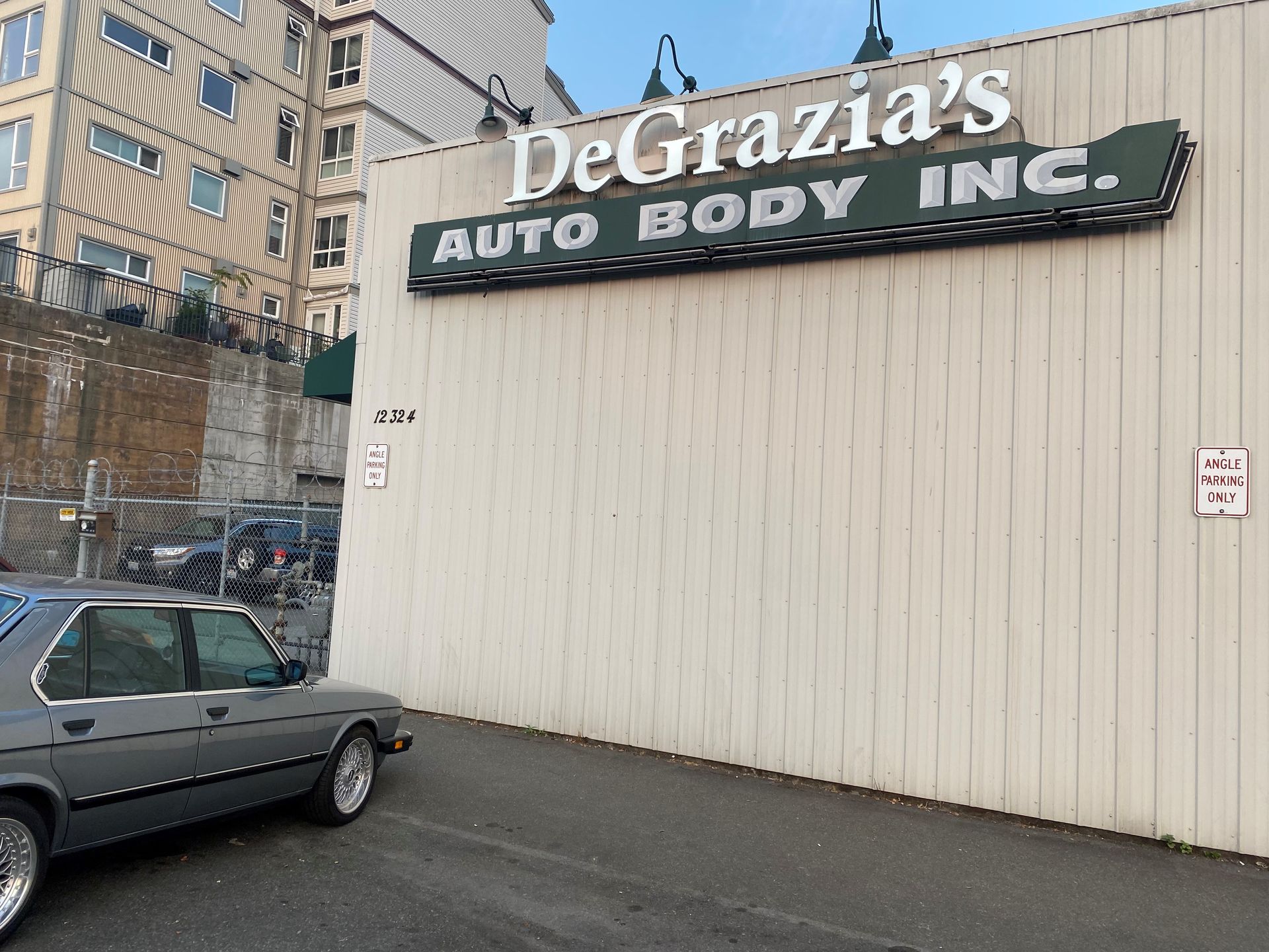 A car is parked in front of a building that says degrazia 's auto body inc.