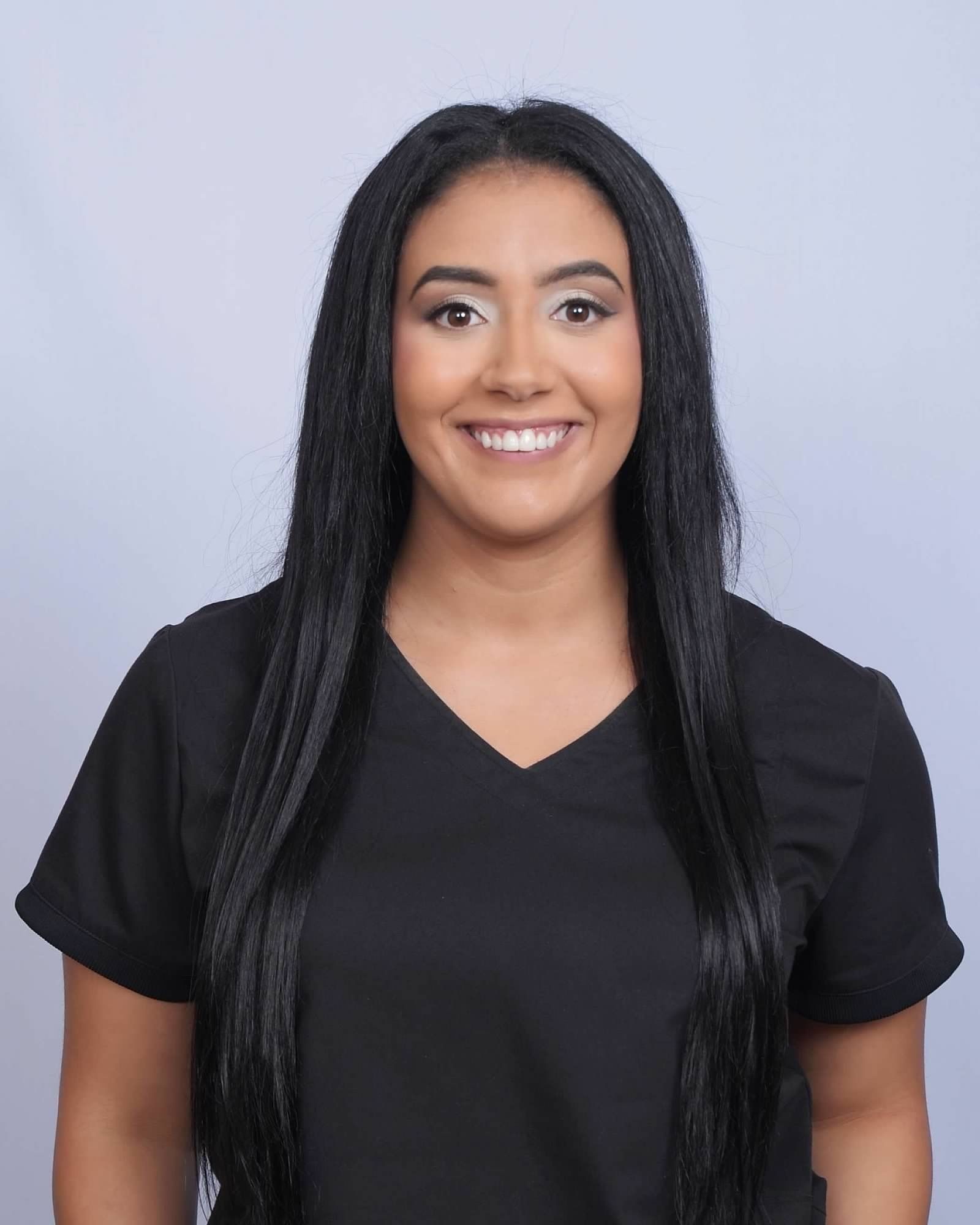 Woman with long black hair smiles, wearing a black top.