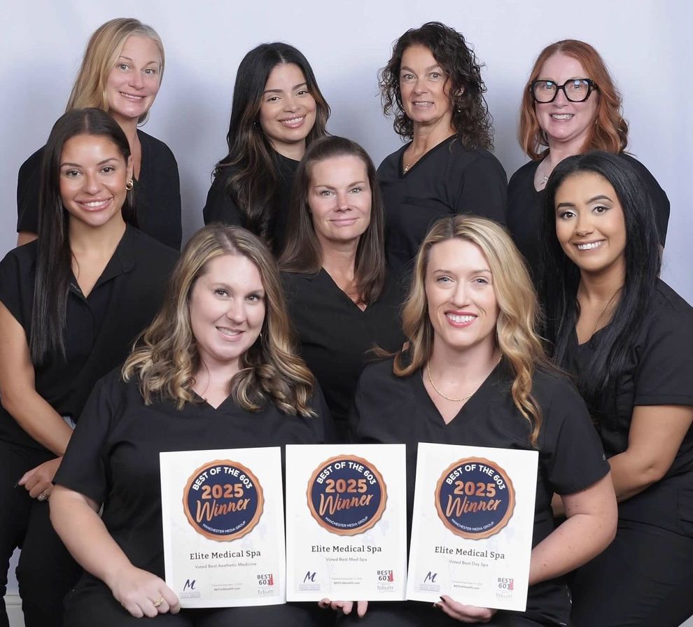 Group of women smiling, dressed in black, posing against a gray background.