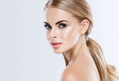 Portrait of a blonde woman looking over her shoulder against a light background