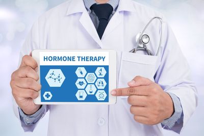 Doctor holding tablet with “Hormone Therapy” graphic and medical icons