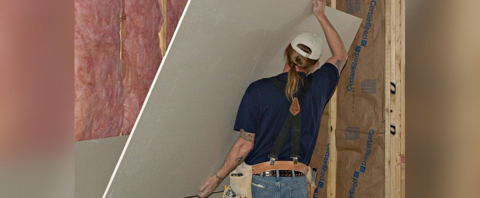 A man carrying a drywall panel
