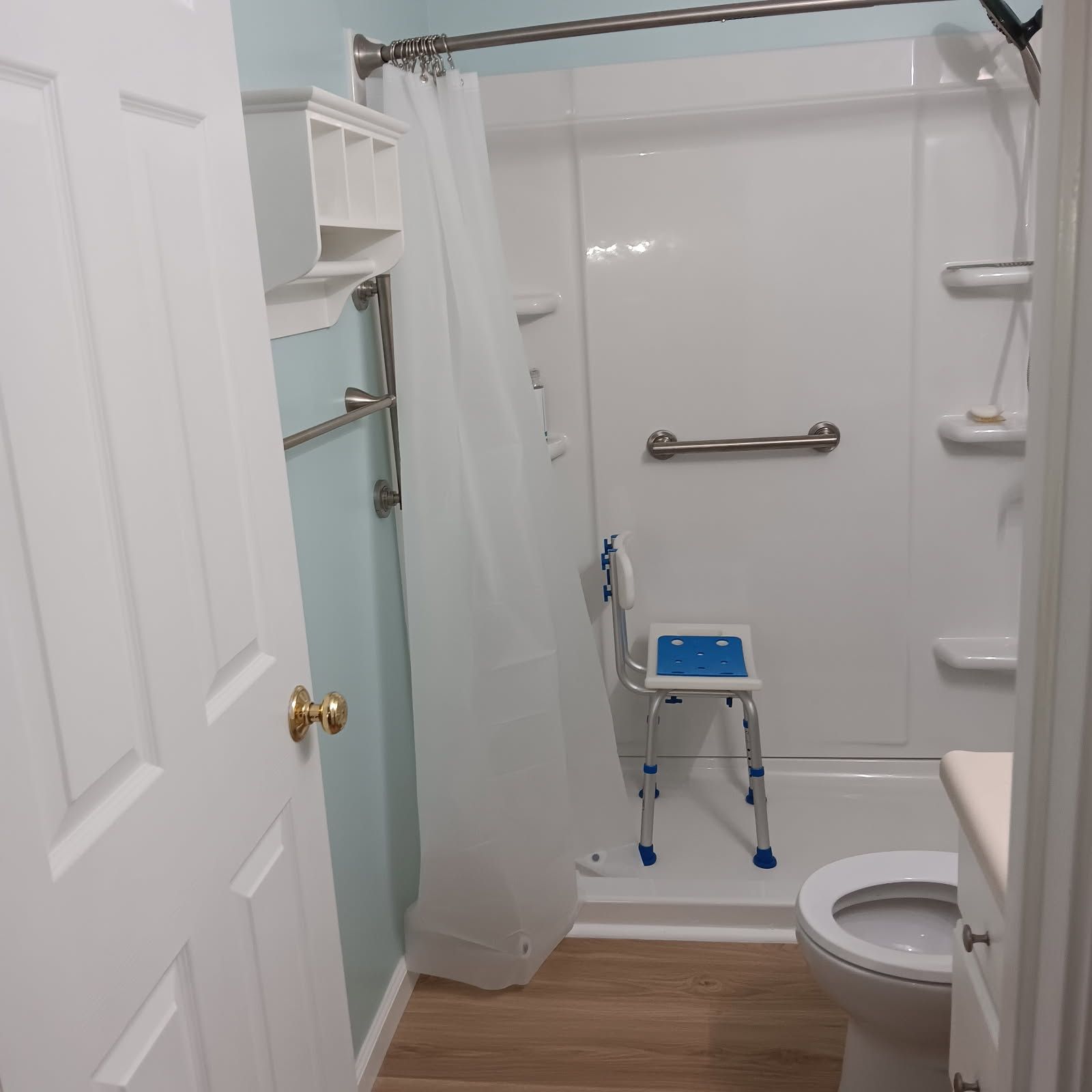 Bathroom with accessible features: shower with a seat, grab bars, and a toilet.