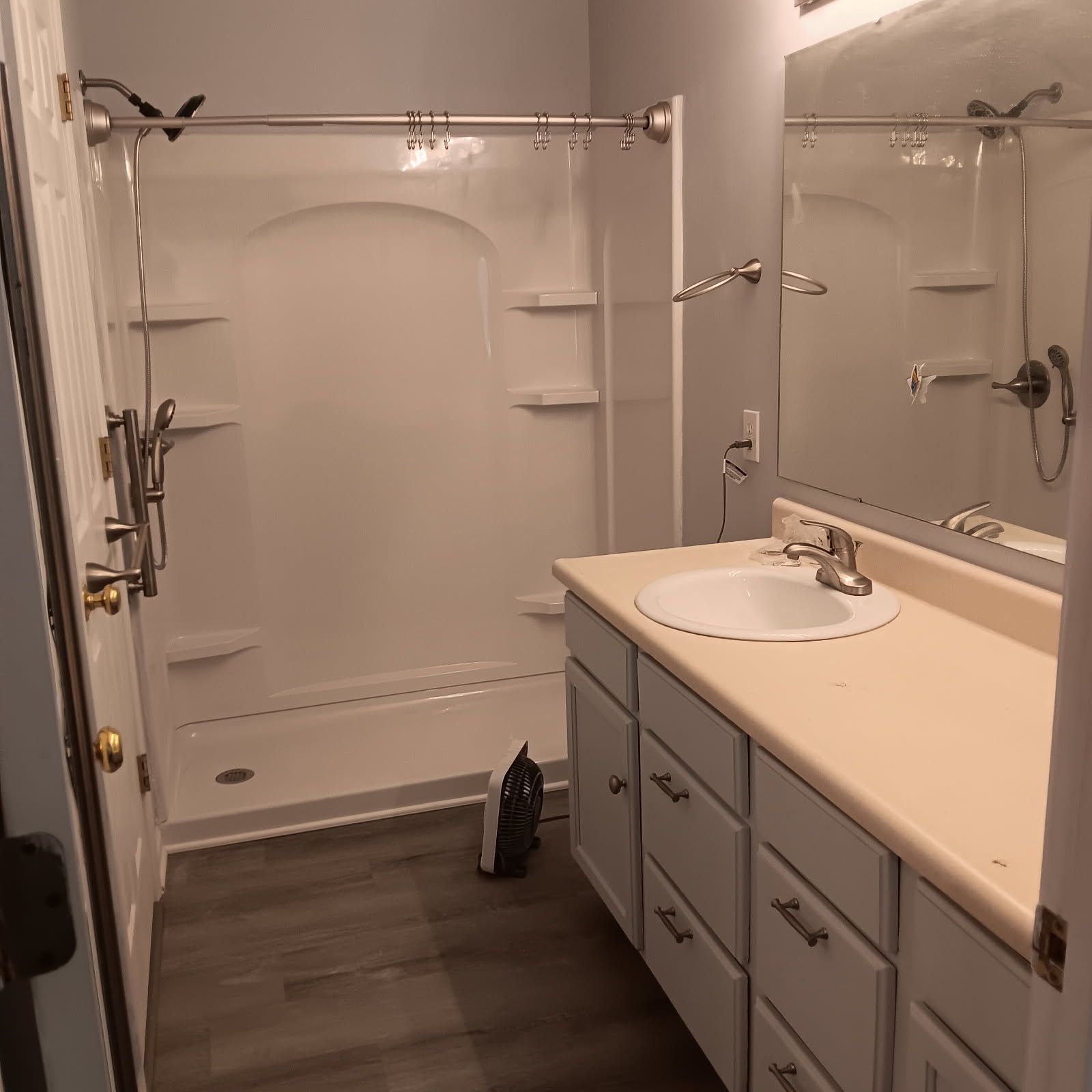 Bathroom with white shower, vanity, and gray walls, with light wood-look flooring.