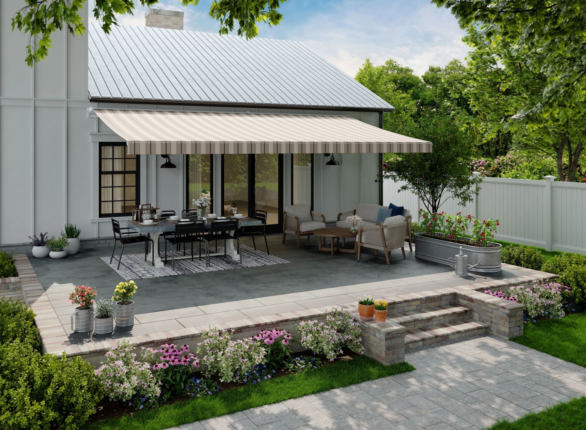 Patio with dining table, wicker seating, and potted flowers beside a white house and awning.