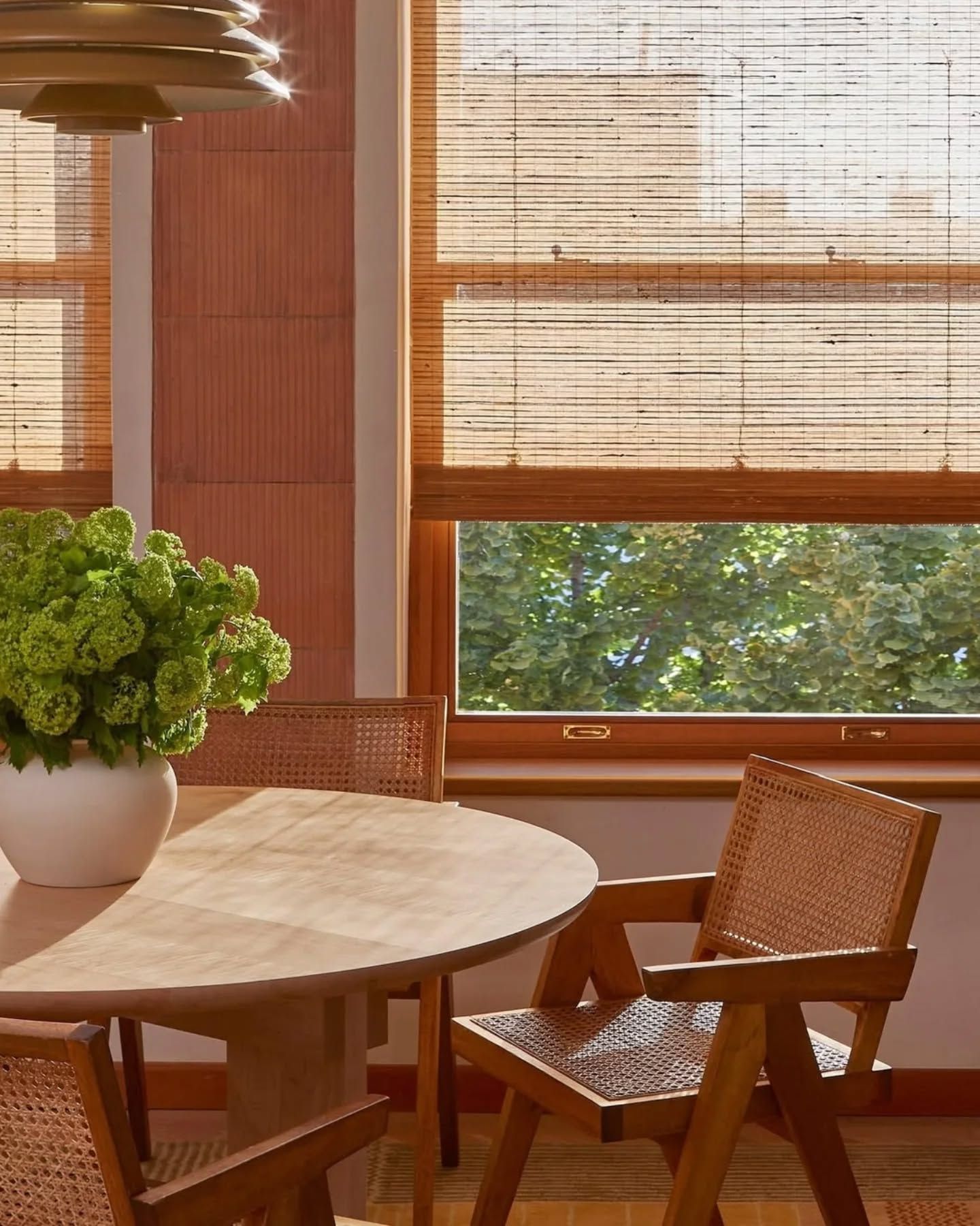 Dining room with a wooden table, woven chairs, and bamboo blinds.