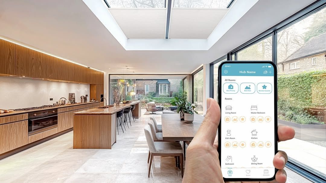 Hand holding a smartphone controls smart home lighting and window shades in a modern kitchen.
