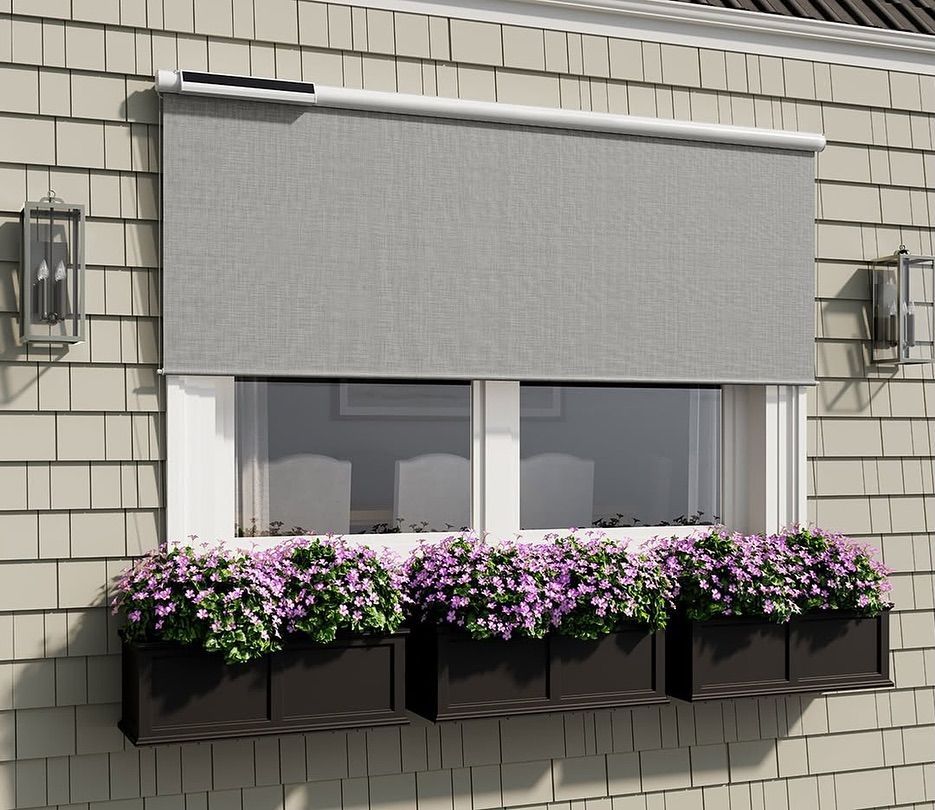 Gray outdoor shade over a window with purple flower boxes.