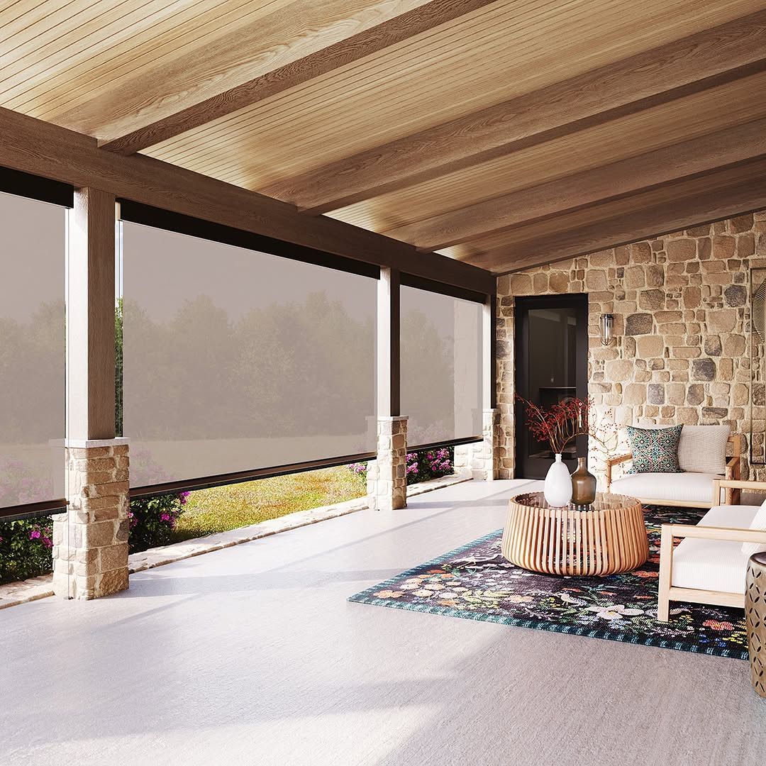 Covered patio with retractable shades, stone wall, furniture, and rug.