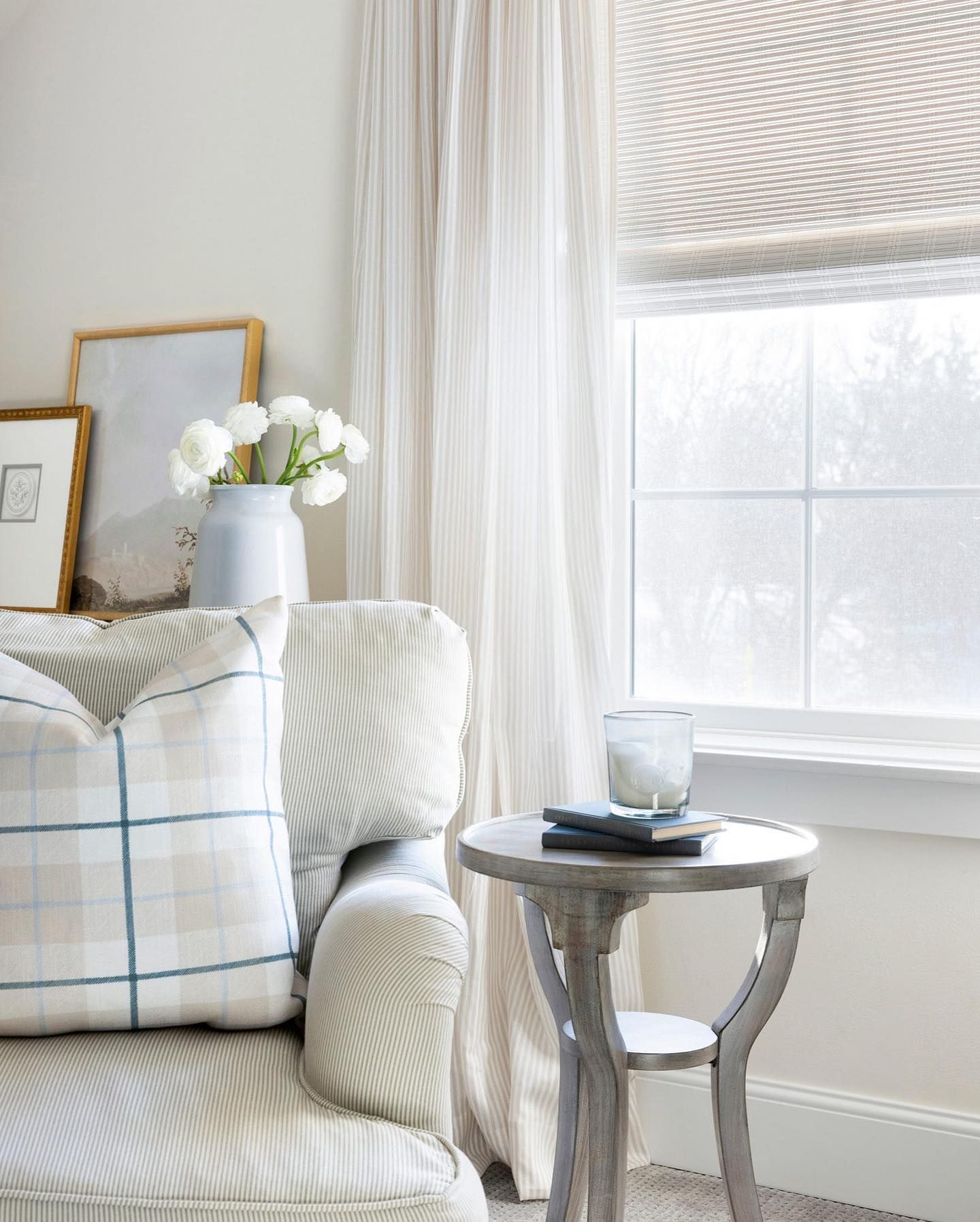 Cozy reading nook with armchair, patterned pillow, small side table, and window with light curtains.