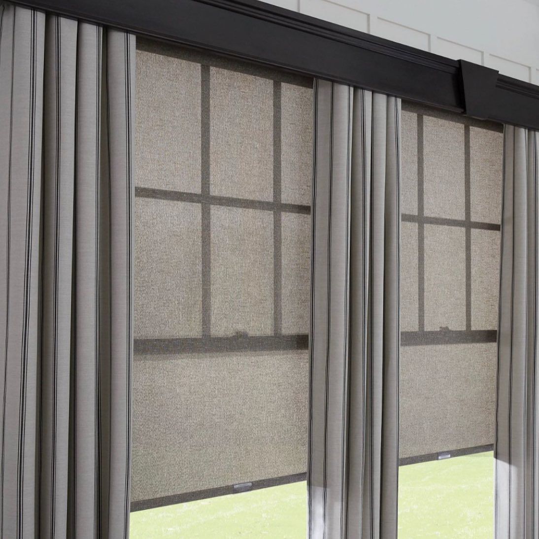Two windows with tan blinds, framed by gray curtains and a dark valance.