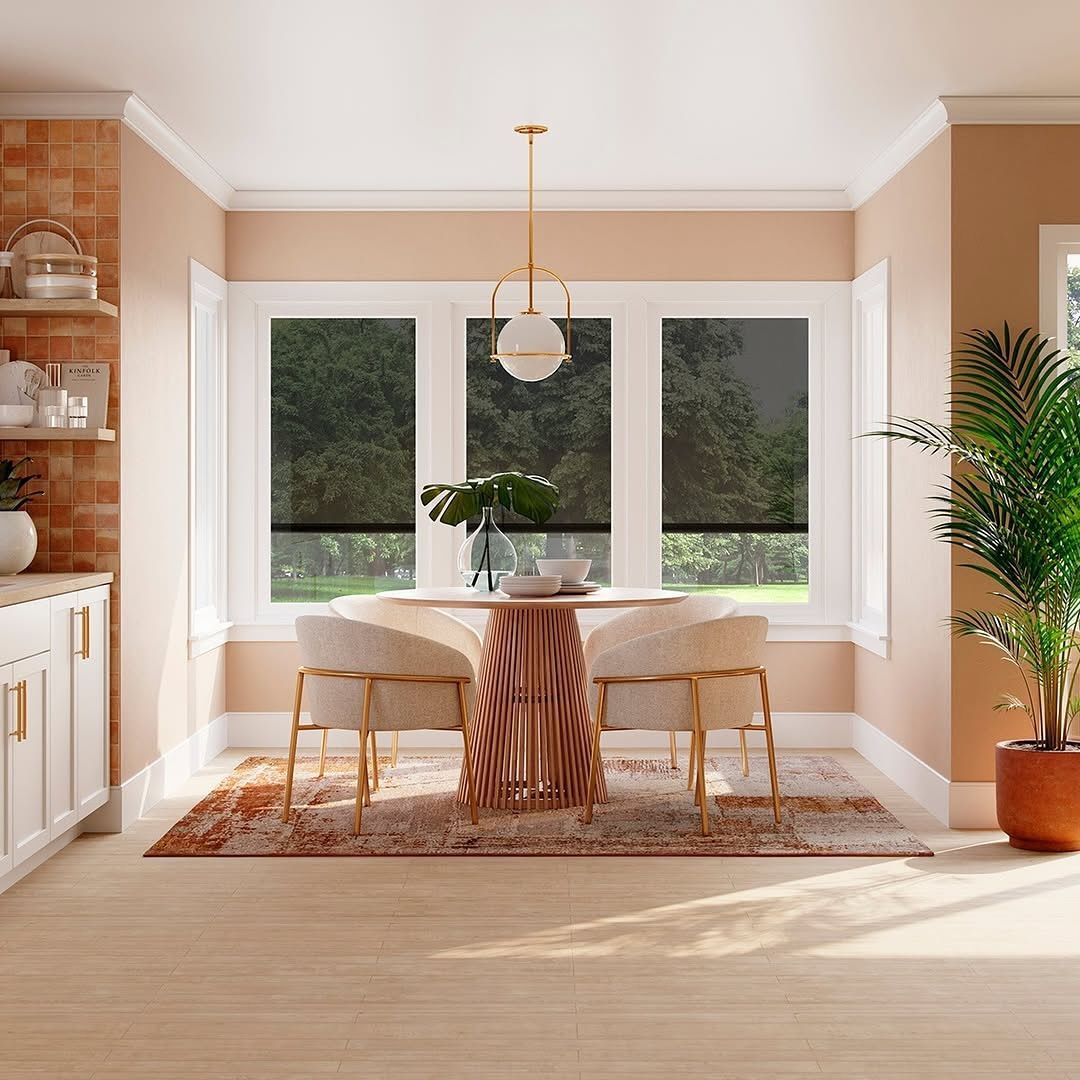 Dining room with table, chairs, windows, and potted plant. Warm color scheme with rug and modern light fixture.