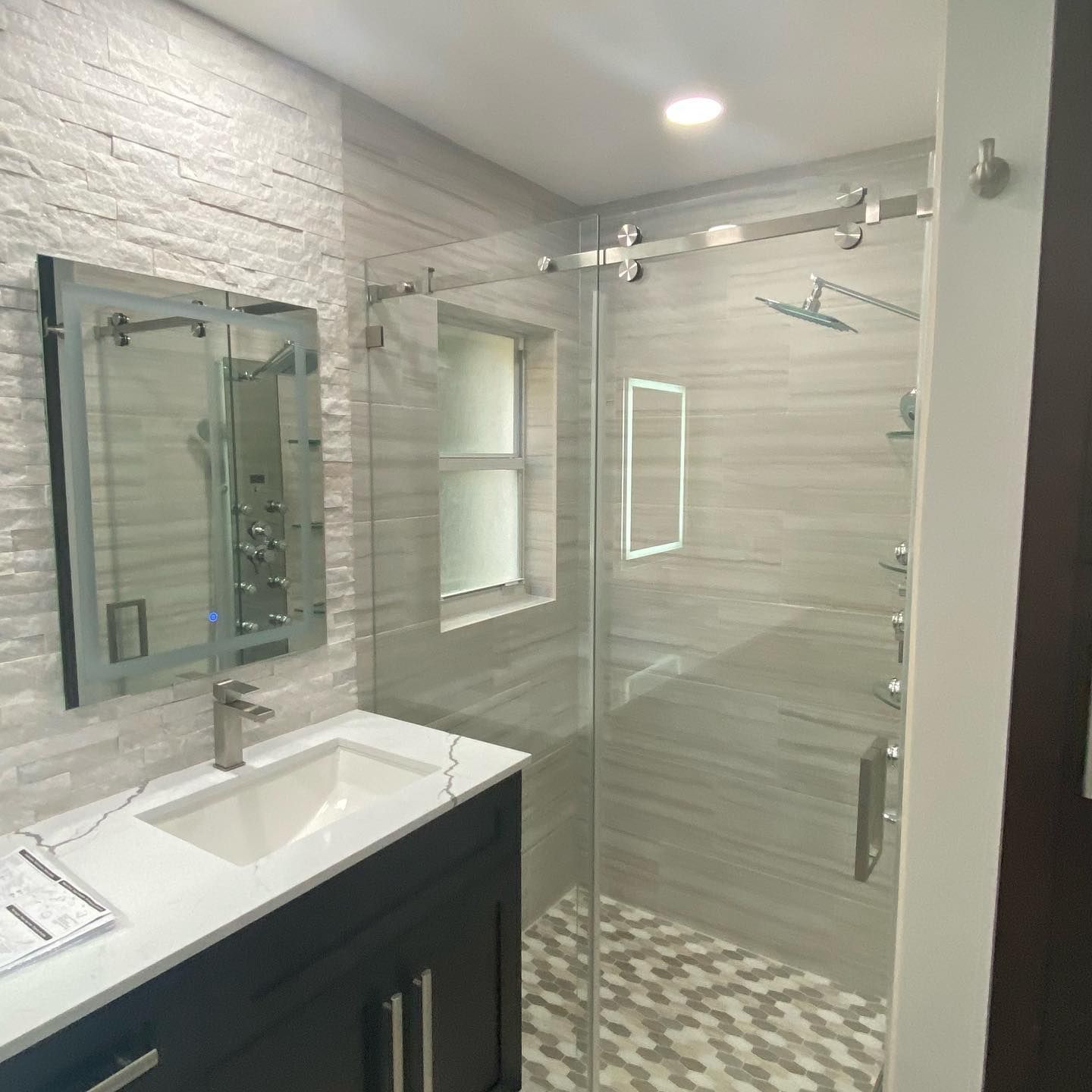 A bathroom with a sink , mirror and walk in shower.