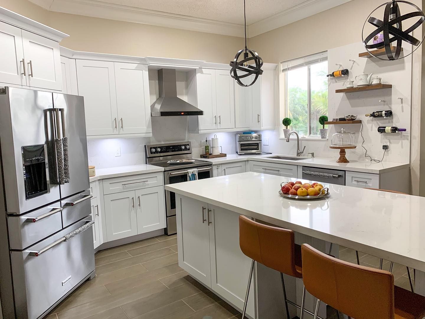 A kitchen with white cabinets , stainless steel appliances , and a large island.