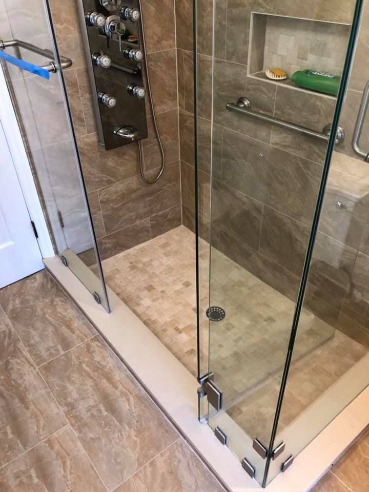 A bathroom with a walk in shower with a glass door.