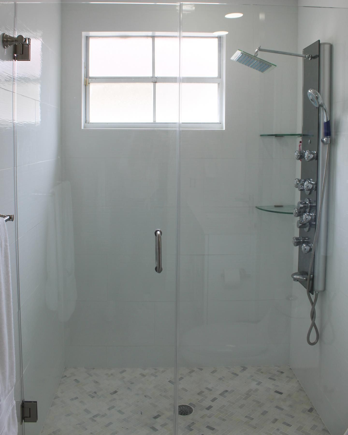 A shower with a glass door and a window