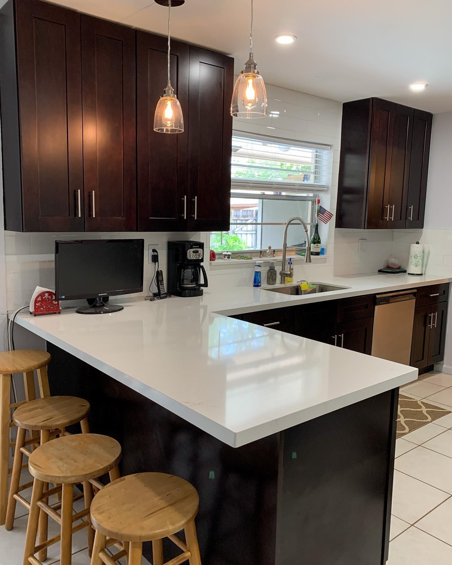 A kitchen with stools and a computer on the counter