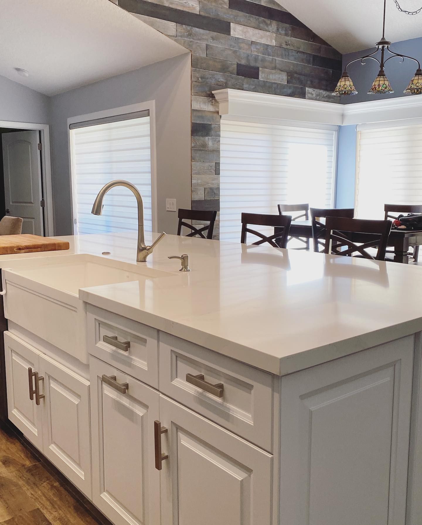 A kitchen with white cabinets , a sink , and a dining room in the background.