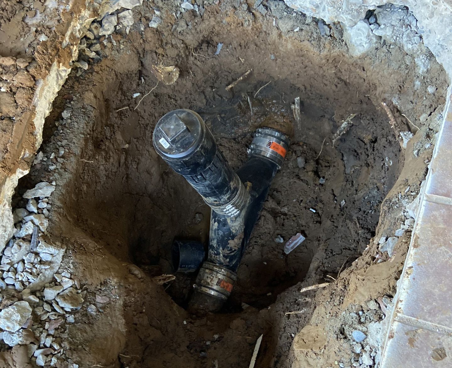A pipe is laying in the dirt in a hole