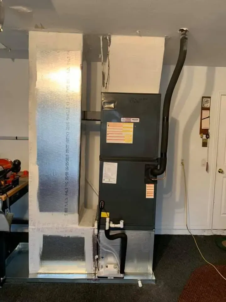 HVAC unit with large metal ductwork in a utility room, black equipment cabinet on the floor