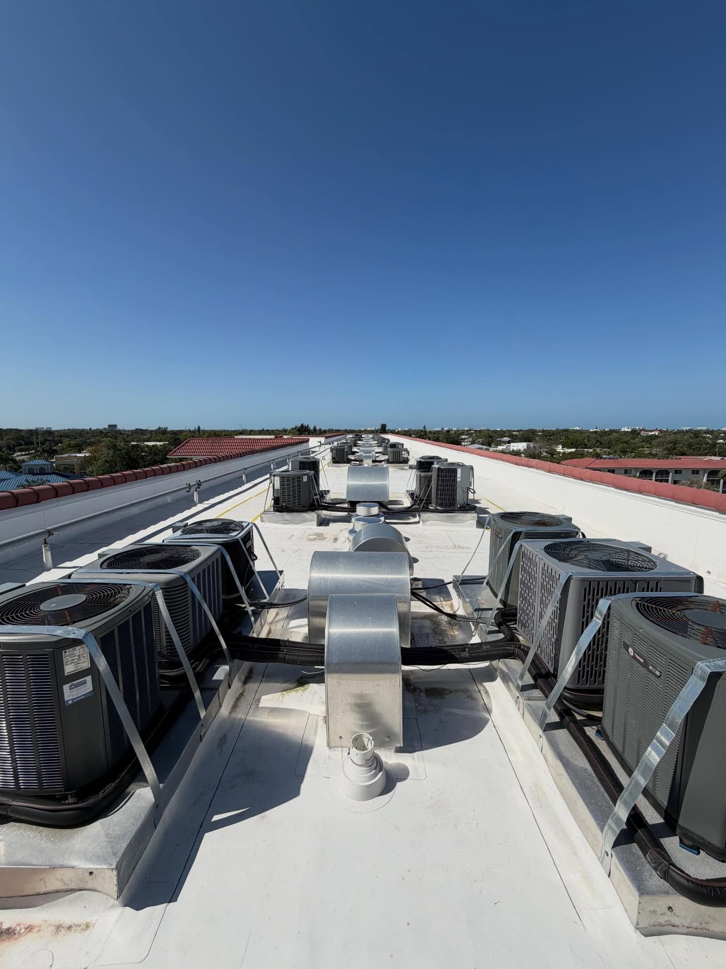 Rooftop HVAC units on a white commercial building under a clear blue sky