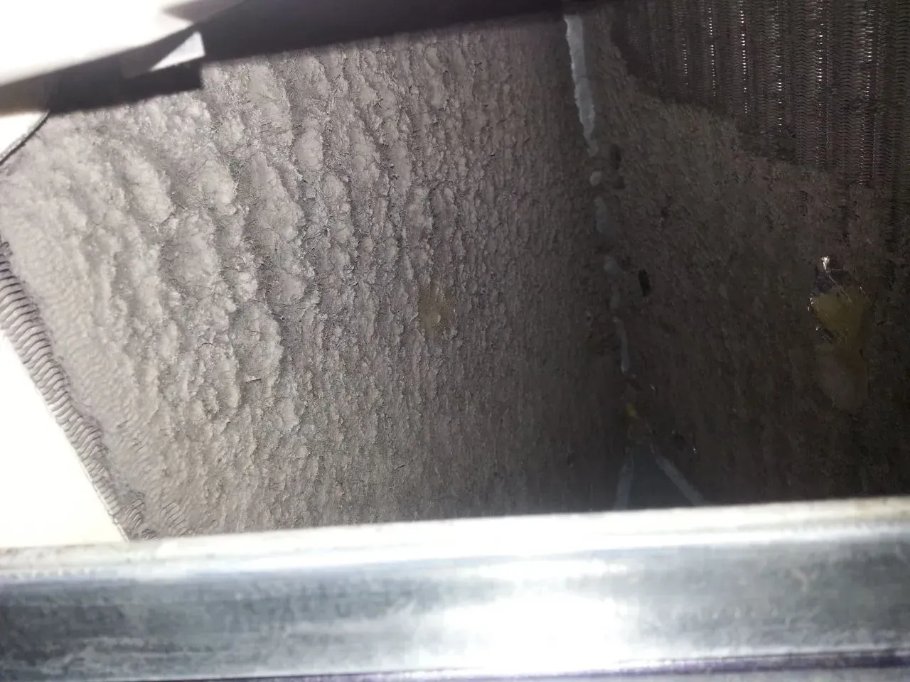 Close-up of a silver metal vent or HVAC duct interior with dark mesh on the right side.