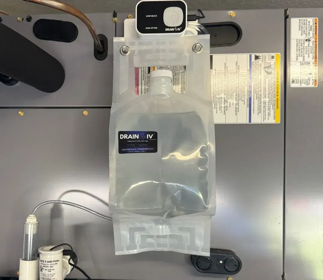 IV fluid bag hanging from a medical pole against a gray hospital wall.