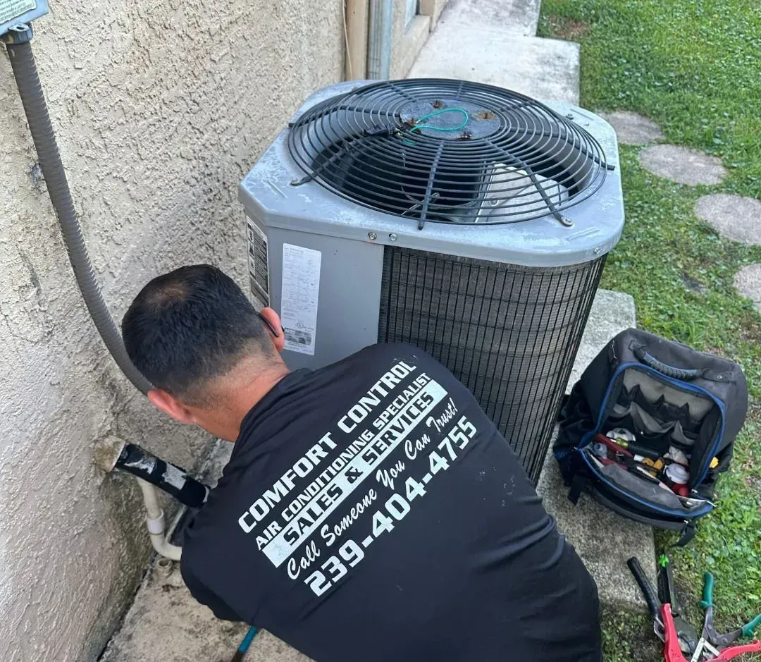 Technician inspecting an outdoor HVAC unit beside a house, with tools nearby.