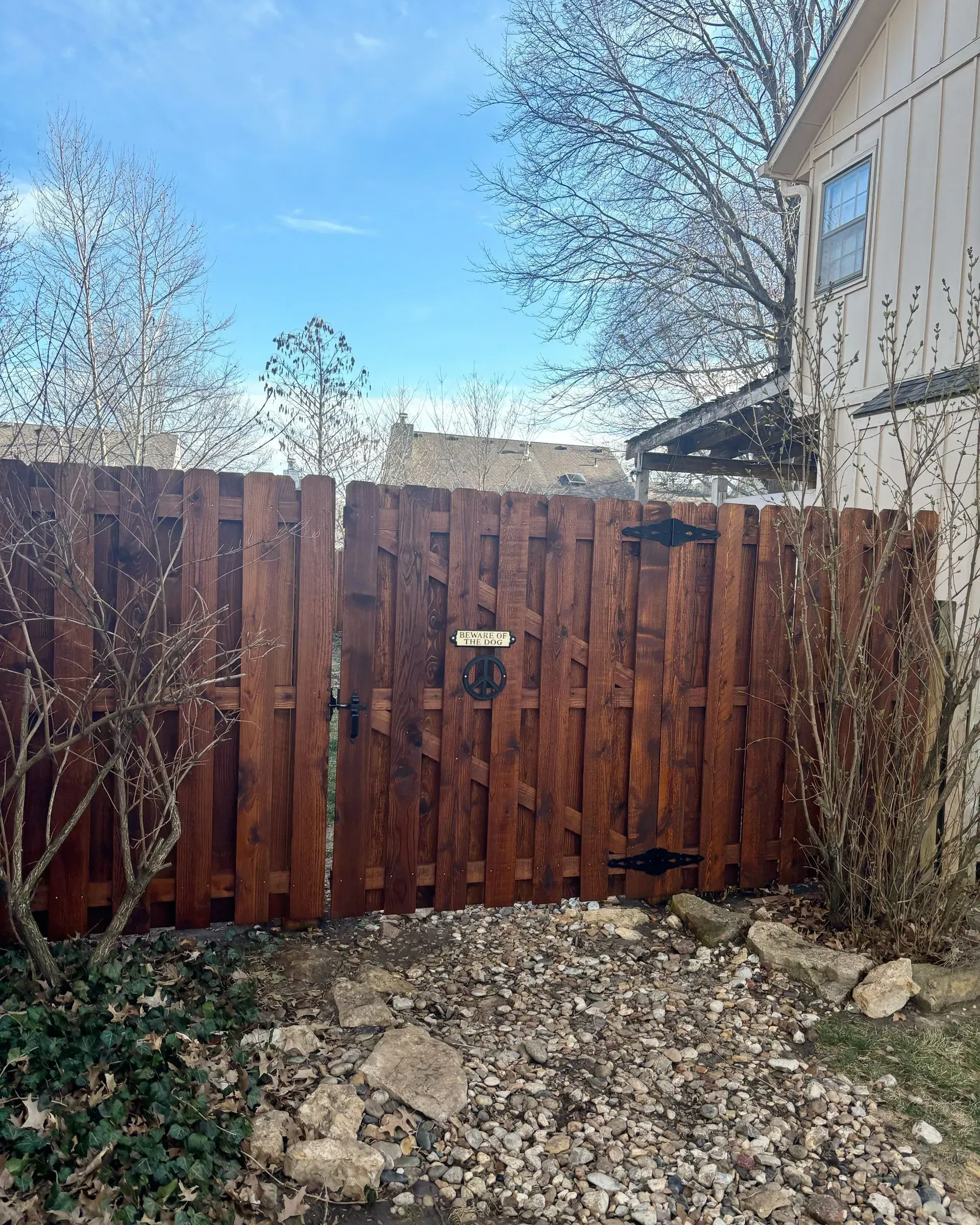 Wooden fence with a gate, stained brown, in a backyard setting.