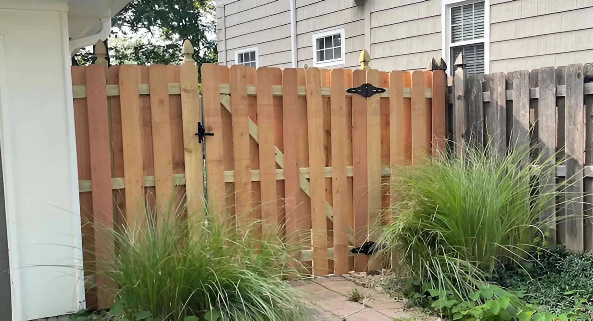 Wooden fence with a gate, plants in front.