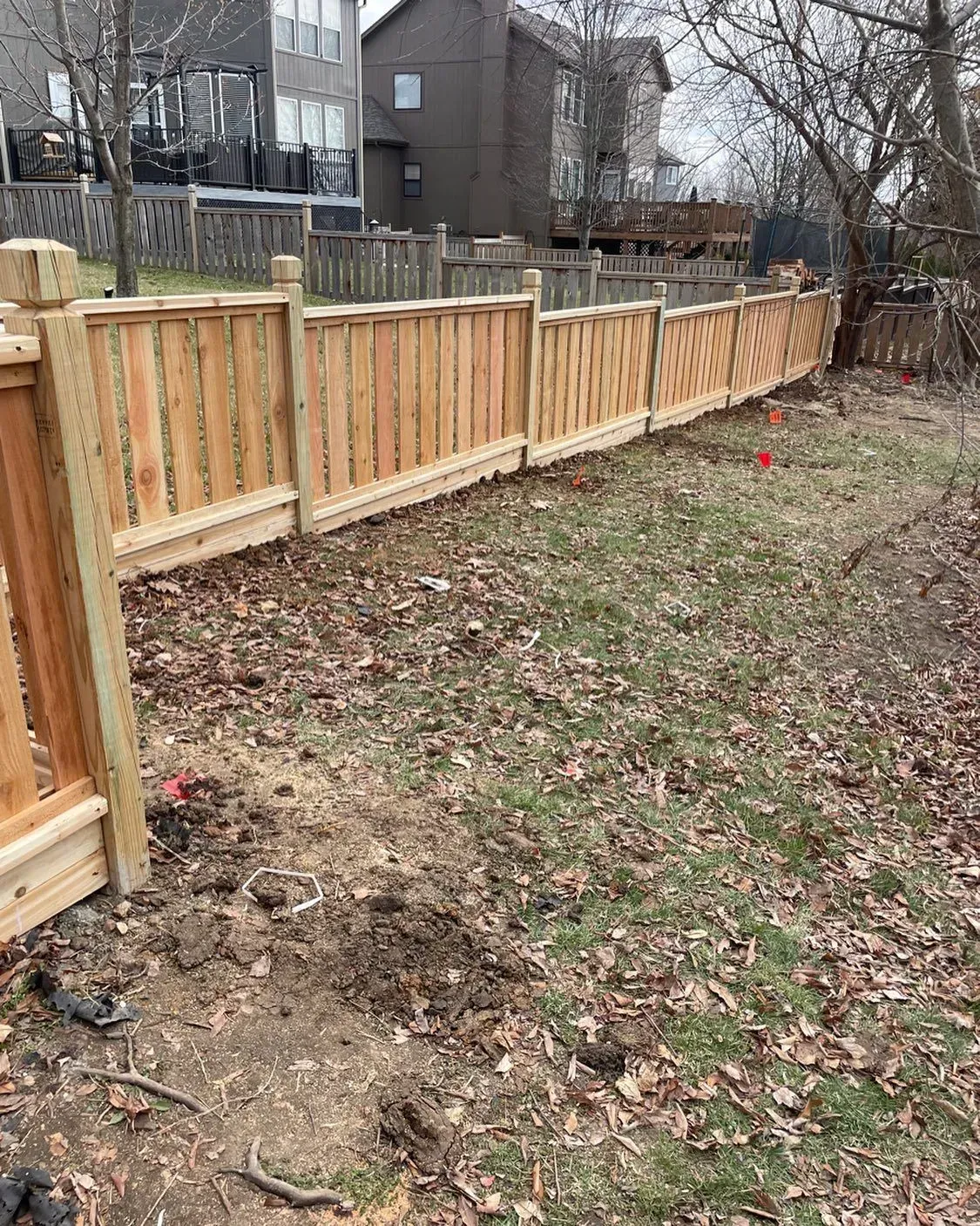 Wooden fence in a grassy yard, with neighboring houses in the background.