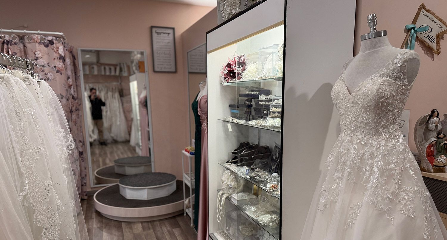 Woman in a beaded white wedding gown with a plunging neckline, surrounded by greenery.
