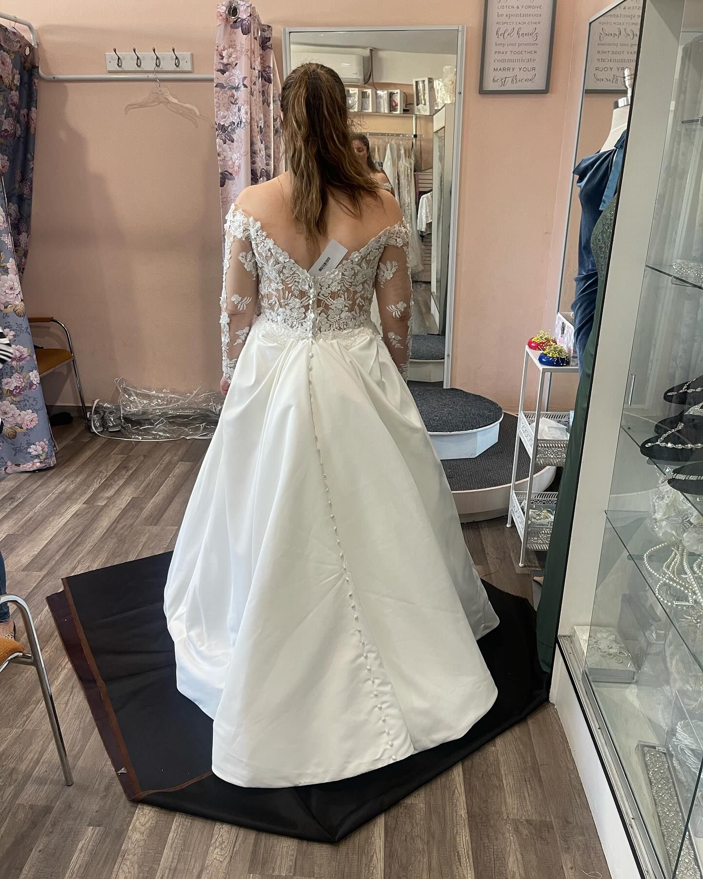 Woman in white wedding dress, back view, trying it on in a bridal shop.