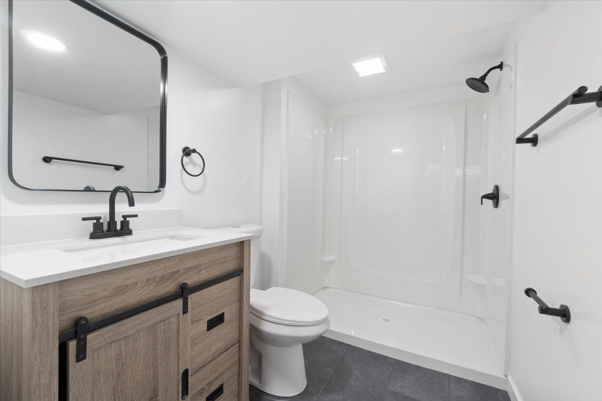 A bathroom with a toilet and sink under a staircase.