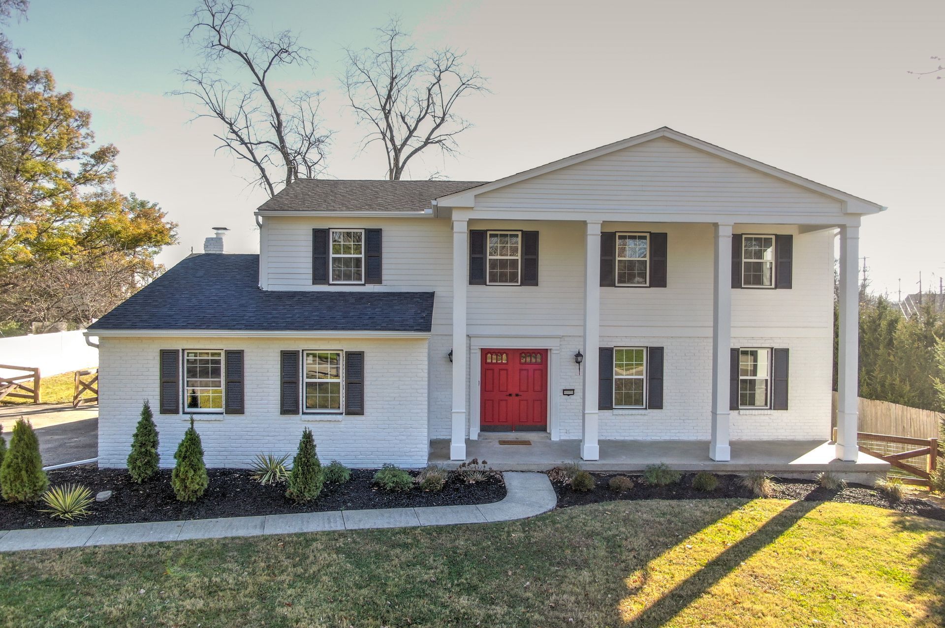 A large white house with a red door and black shutters.