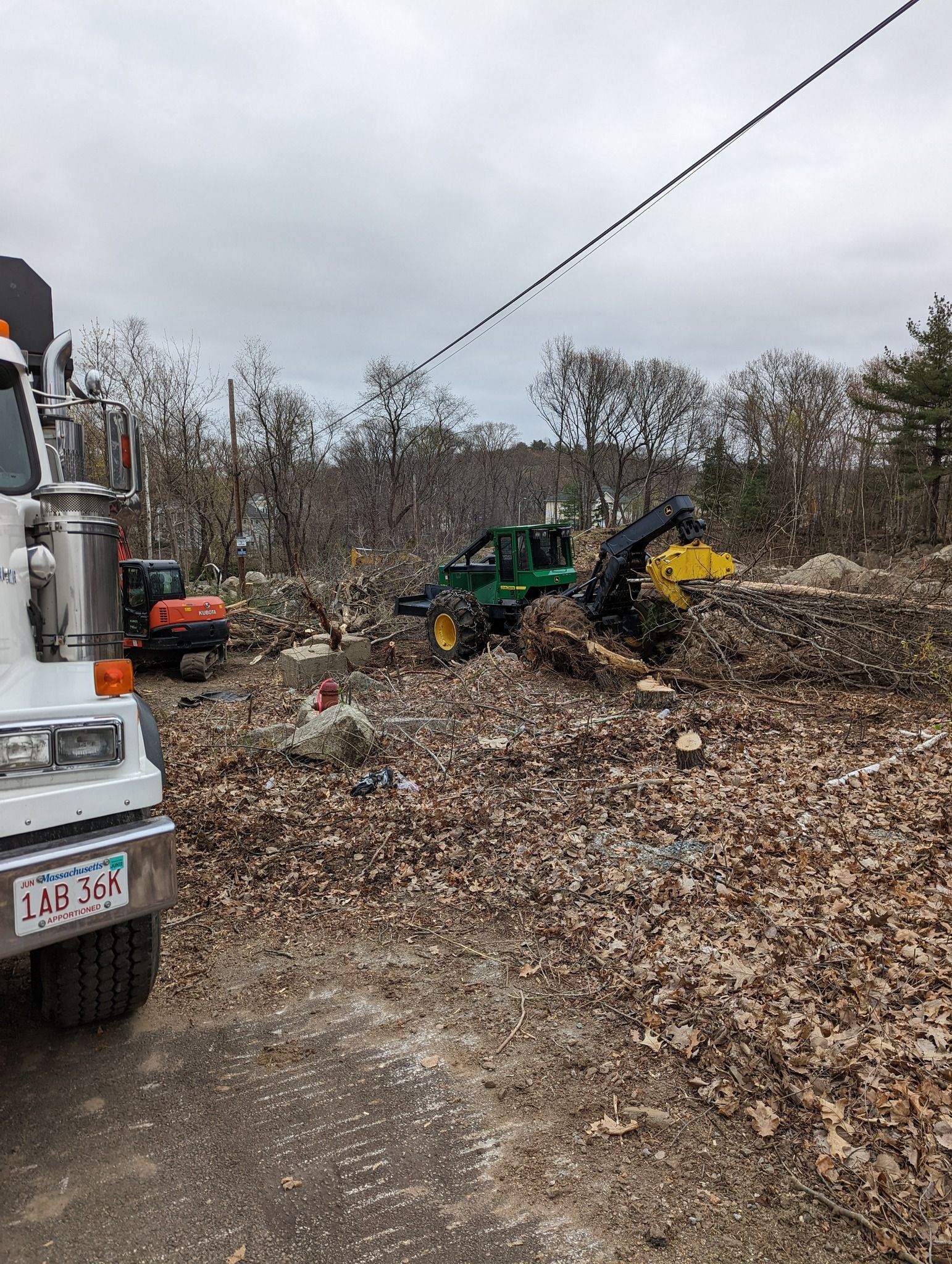 Truck and equipment clearing a debris-filled forest area, including a wood chipper.