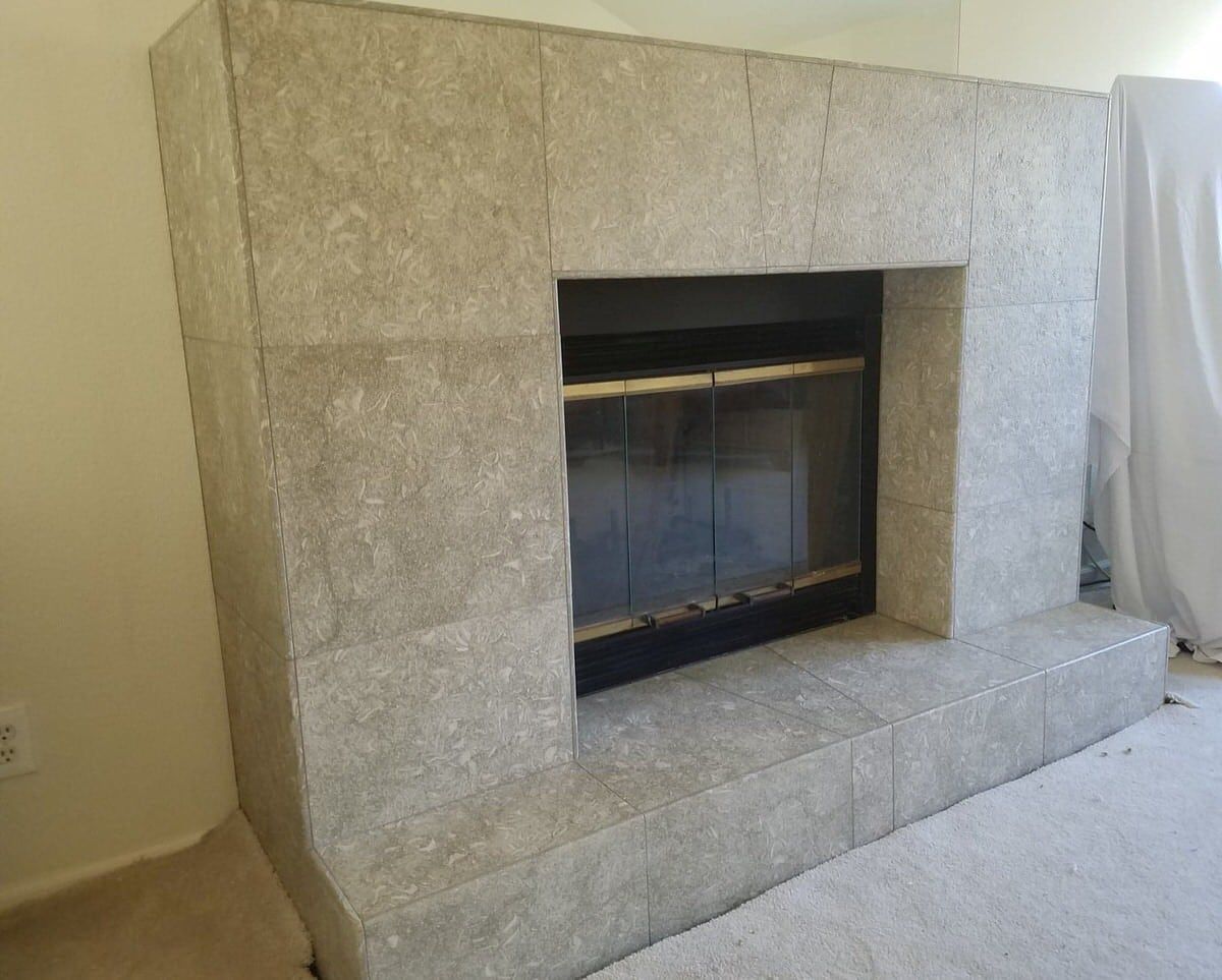 Gray tiled fireplace with black firebox and glass doors.