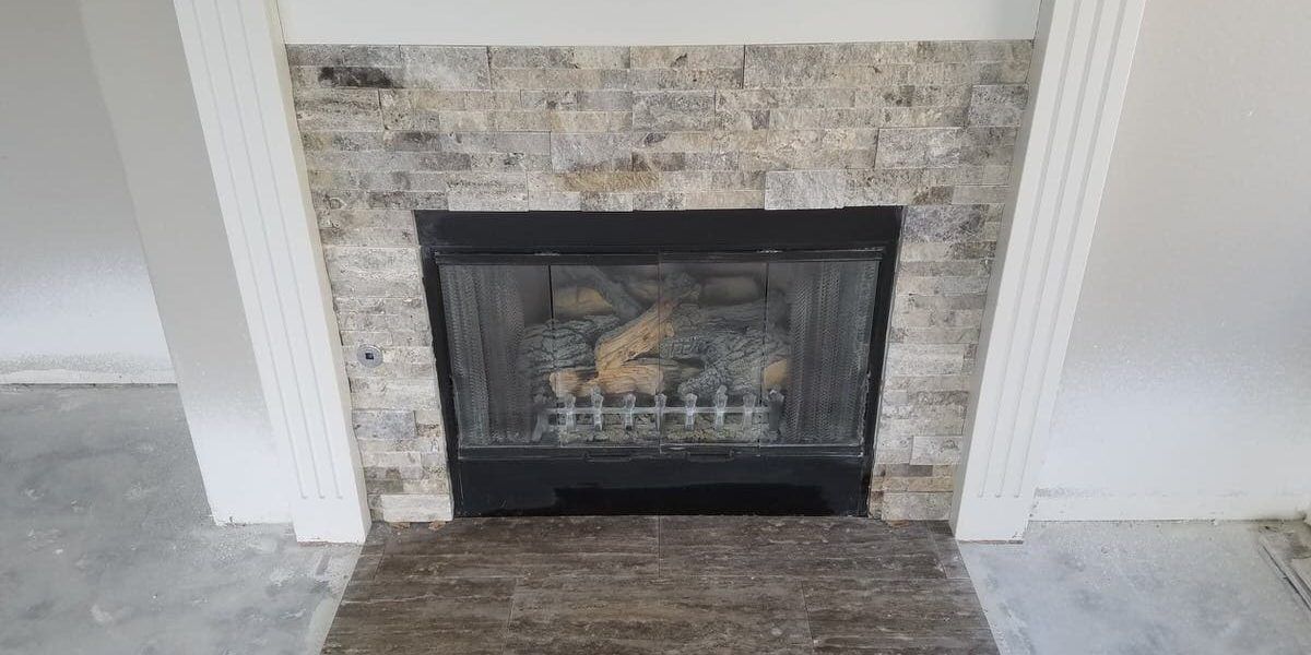 Fireplace with stone surround and white trim in a room with unfinished flooring.