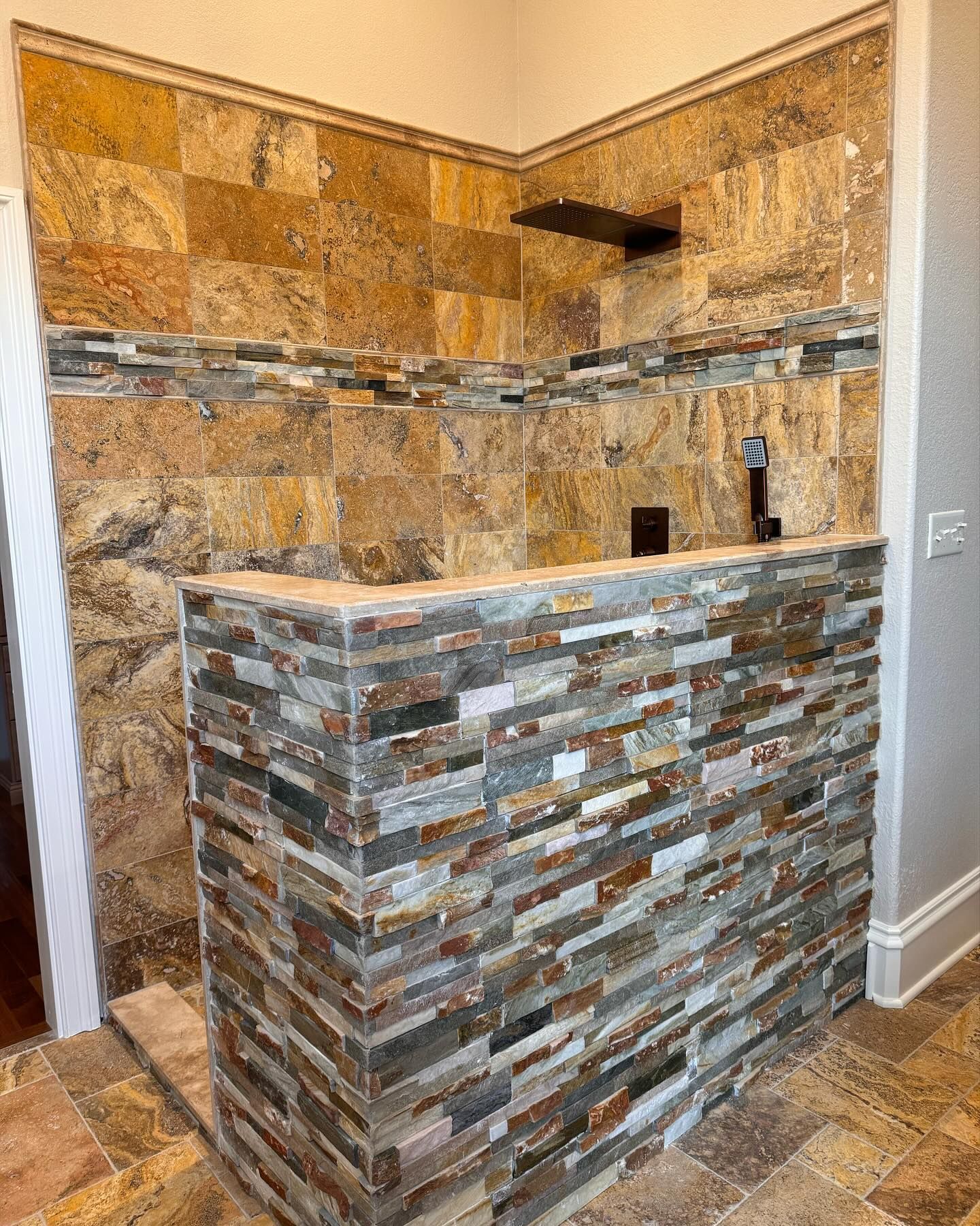 Bathroom with stone tile walls, varied colors, built-in shelf, and stone accent band.