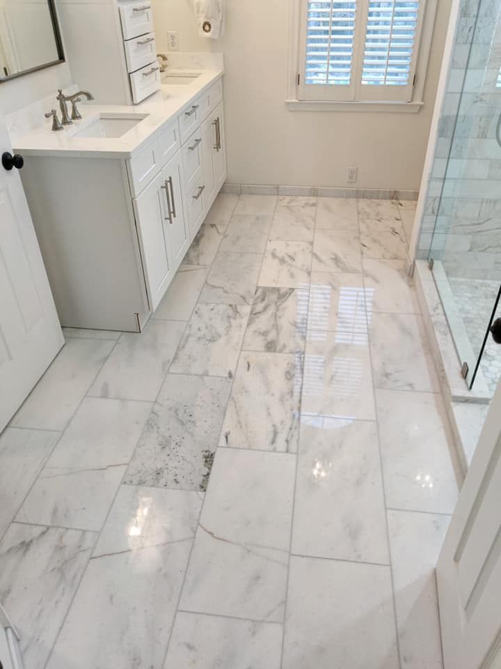Bathroom with white marble tile floor, white cabinets, and a glass shower.