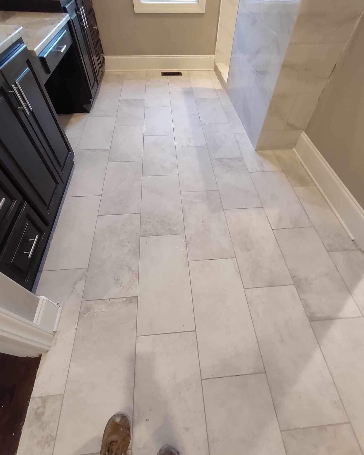 Gray tiled bathroom floor with dark cabinets.