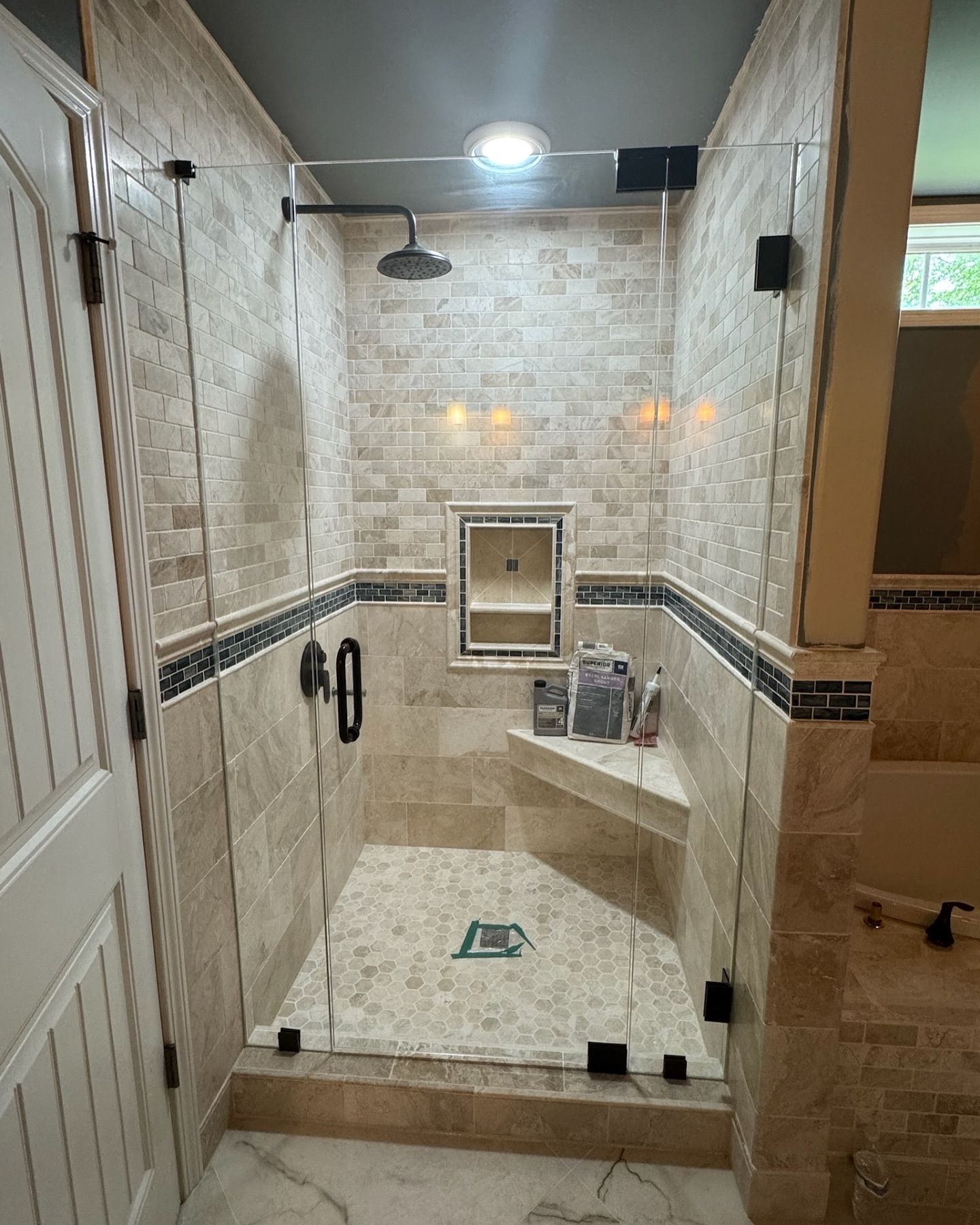 A tiled shower with glass doors, a built-in bench, and a rain shower head.