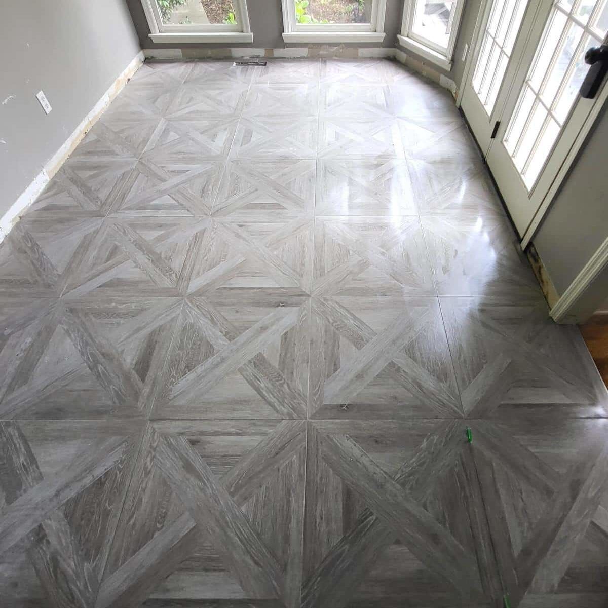 Gray patterned tile floor in a room with a door and windows.