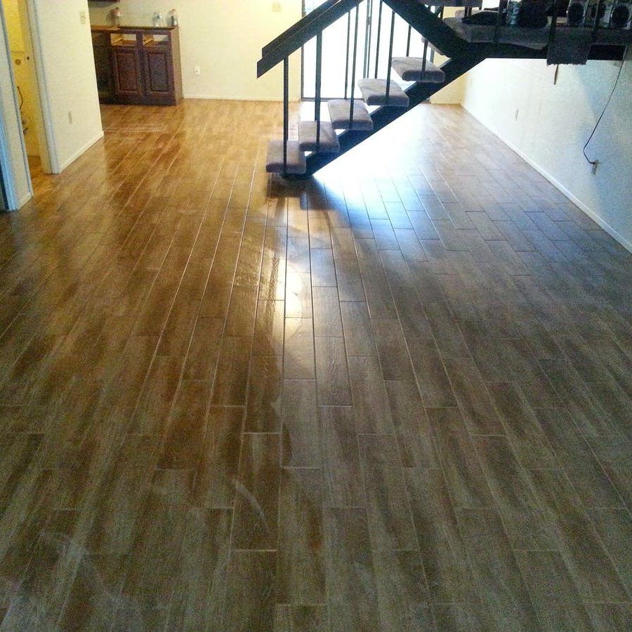 Wooden tile flooring in a room with stairs and a cabinet in the background.