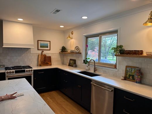 Modern kitchen with dark blue cabinets, white countertops, and stainless steel appliances.