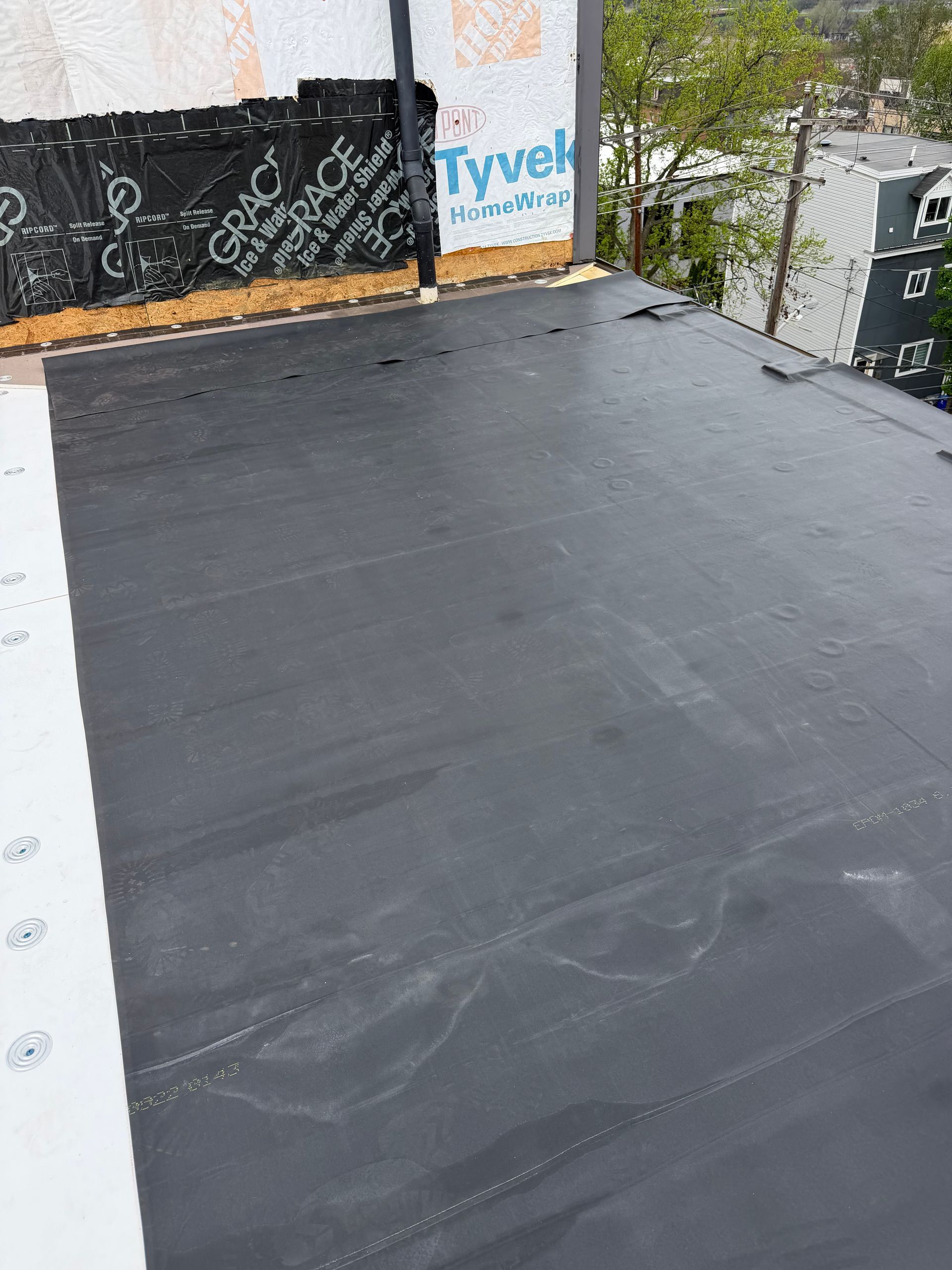 Flat black rooftop surface with construction materials and building walls in the background.