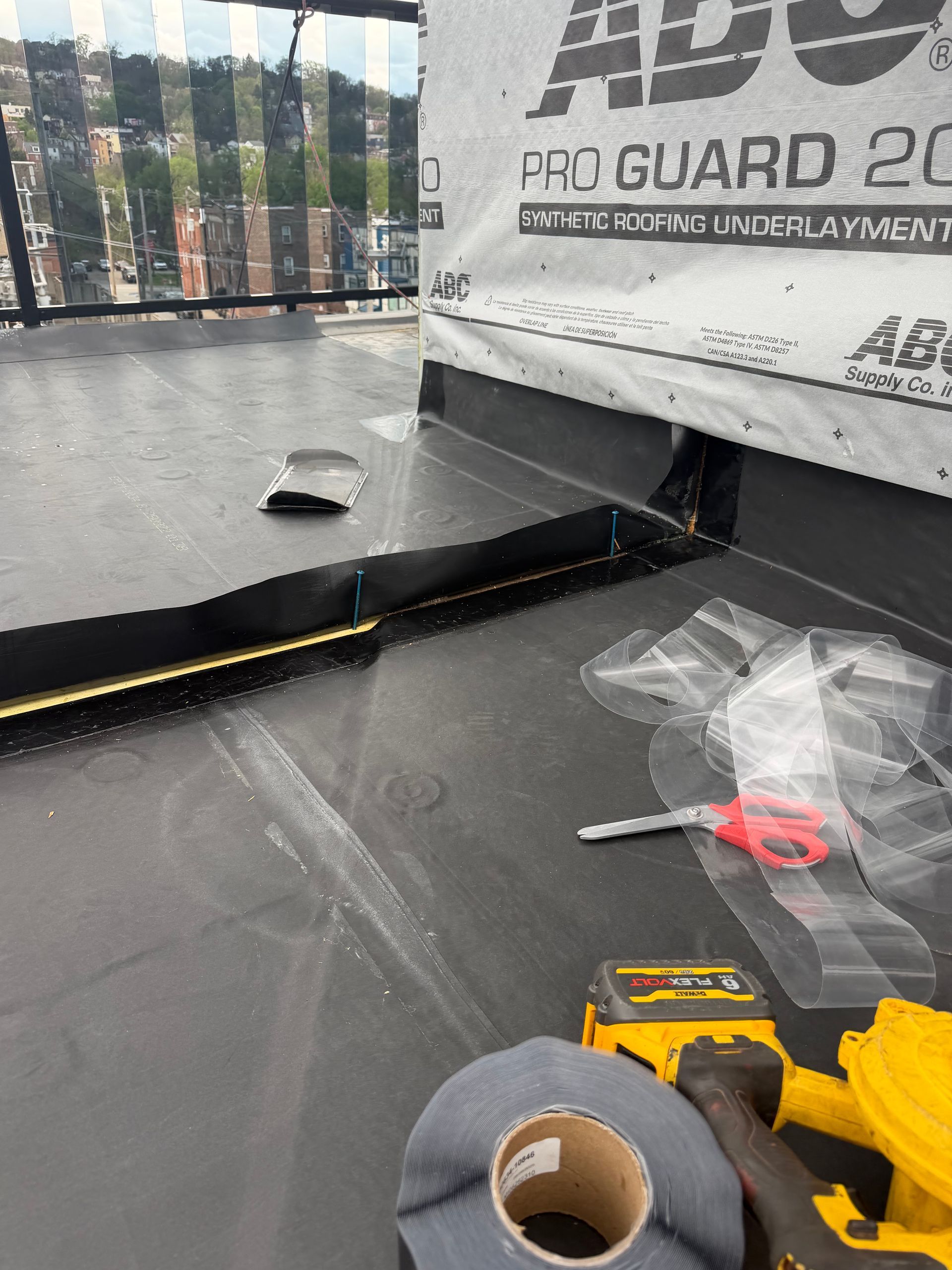 Black workbench with tools, tape roll, and clear plastic bags under a metal shelf panel