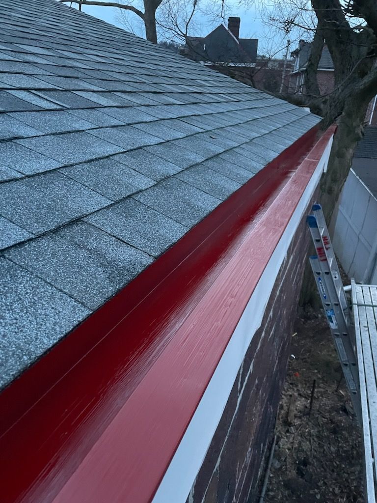 Red roof flashing along a gray shingled roof on a house exterior.