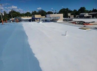 Flat commercial roof partially coated with light blue and white sealant.